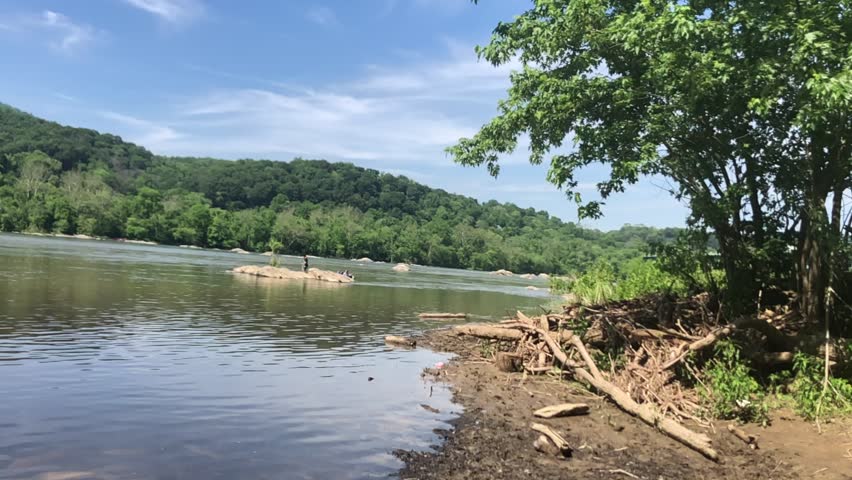 People exploring large rocks within the moving water of Potomac River in Louden County, VA, USA.