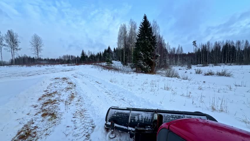 Snowy landscape with a tractor clearing a path, serene winter scene