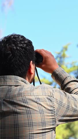 Rear view of a man observing nature with binoculars
