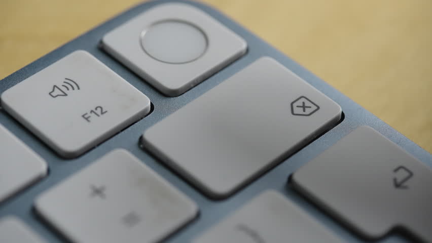 Extreme close up of a finger repeatedly pressing the backspace button on a sleek white keyboard. Ideal for concepts of editing, error correction, and data deletion.