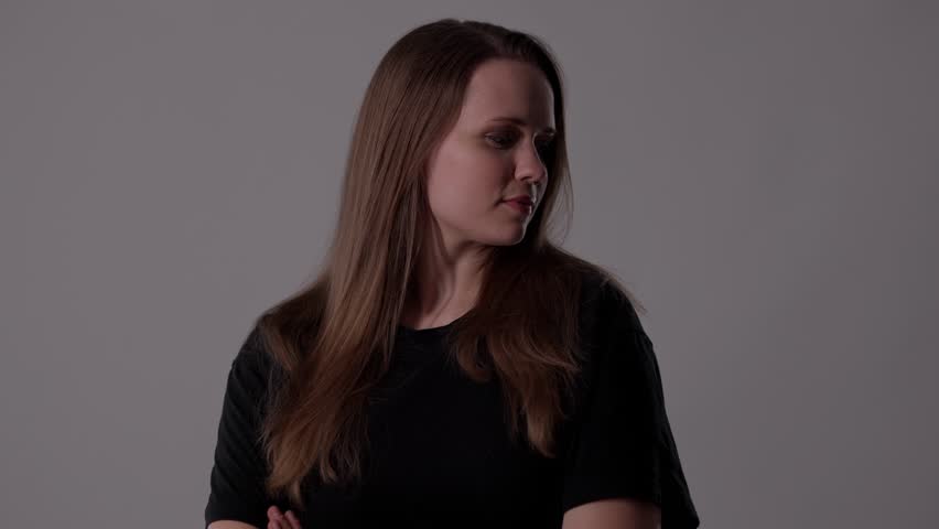 Studio portrait of a young woman holding her brown hair with hands behind her head