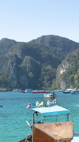 A traditional longtail boat cruises past limestone cliffs on turquoise water under bright sunny skies