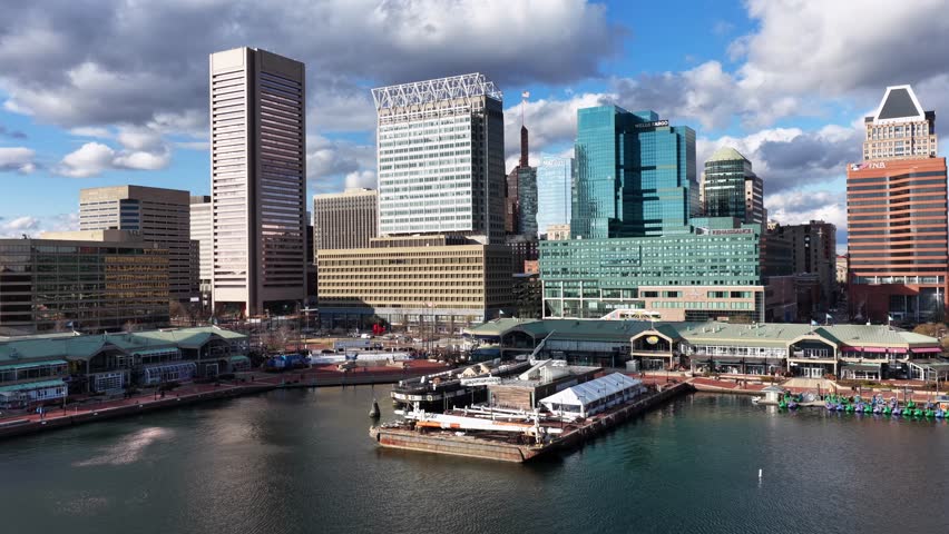 Aerial view of Nashville skyline with modern skyscrapers, waterfront buildings and Cumberland River, showing city’s downtown architecture under partly cloudy sky. Wide shot.