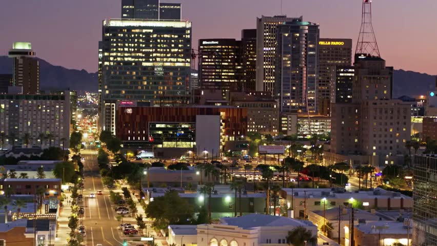 Downtown Phoenix, Arizona skyline at dusk with glowing city lights and modern architecture, showcasing an urban desert city atmosphere.