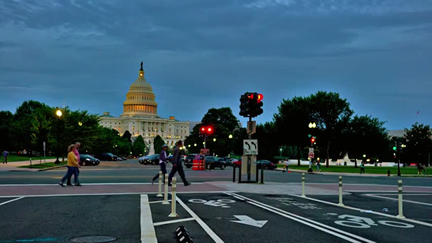 People crossing the street in front of the U.S. Capitol at twilight, ideal for politics, city life, travel, and government-themed projects.