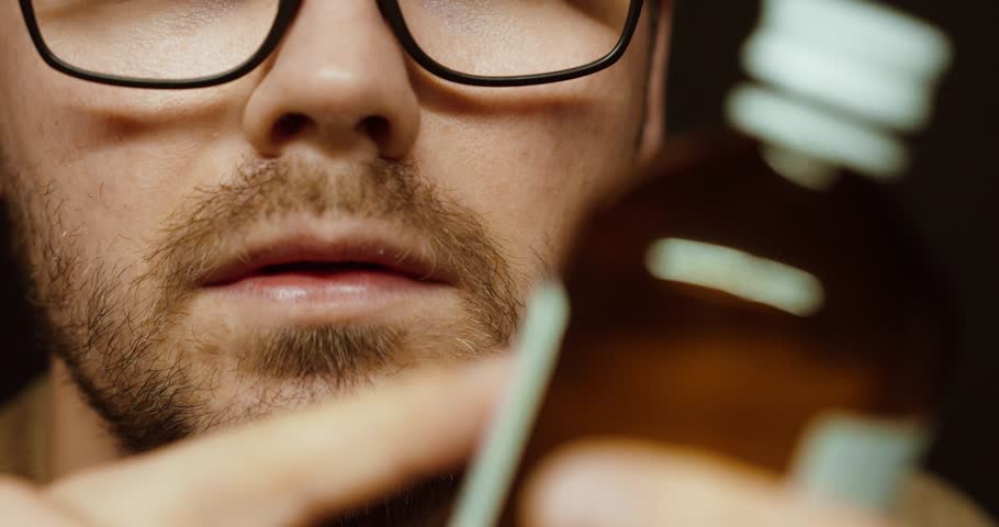 Close-up of a man with glasses carefully reading the label on a medicine bottle. Concept of healthcare, medication safety, dosage checking, and medical awareness.