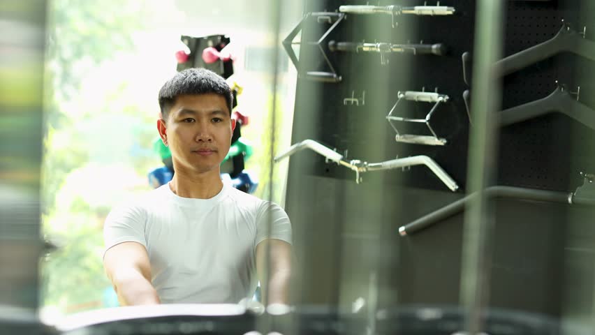 Athletic man performs seated cable row exercise in a modern gym for strength training.