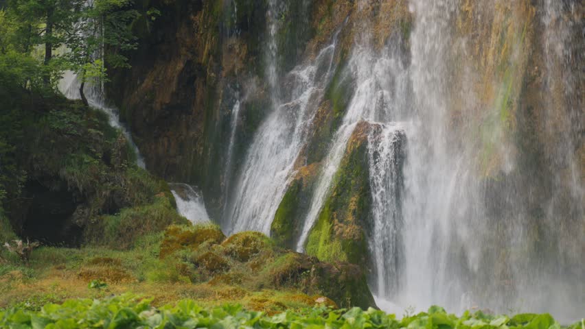 Detailed view of multiple waterfalls flowing over mossy rock formations in Plitvice Lakes National Park, Croatia.