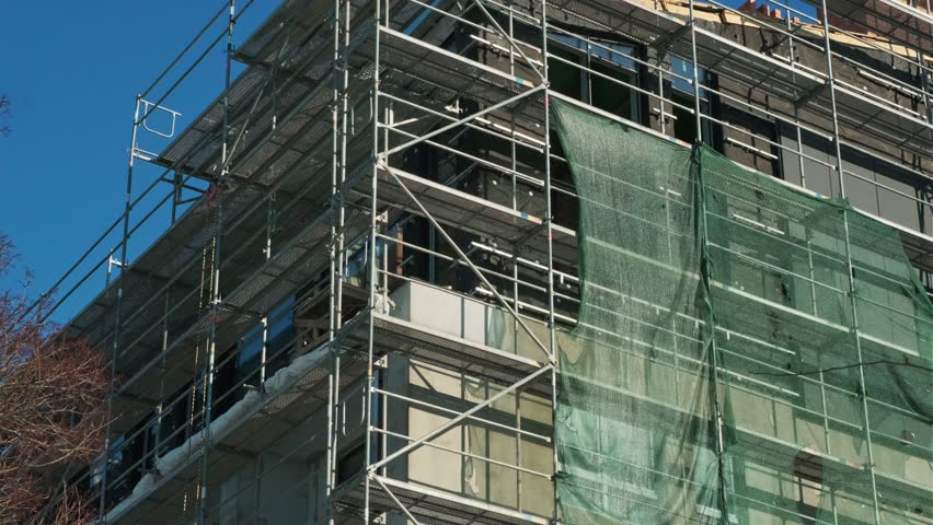 Scaffolding erected around a building under renovation. Construction industry site with metal structure for repair work on a facade.