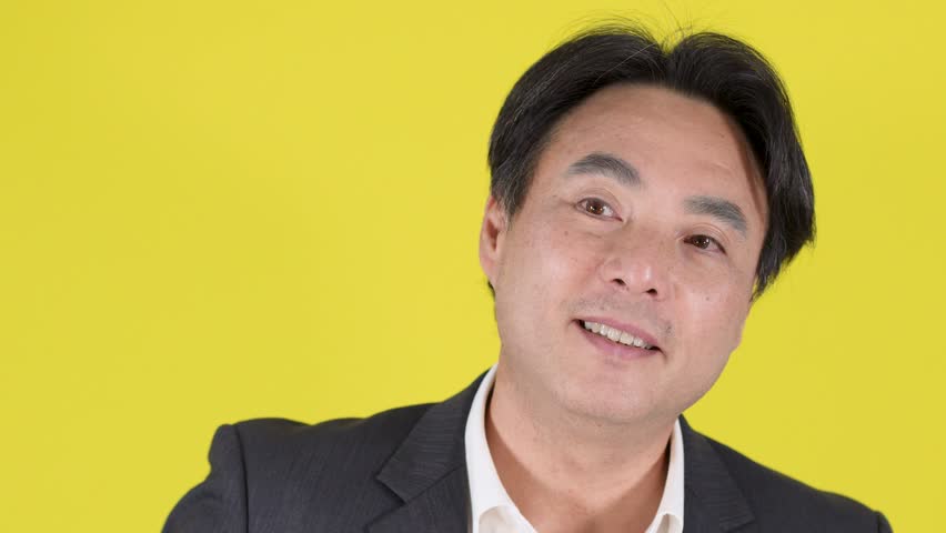 Man in formal suit glances at wristwatch, expressing impatience, under bright studio lighting