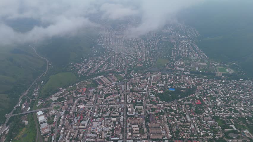 An aerial view of a city located in a mountainous region. Aerial view Vanadzor town in Lori region of Armenia, Caucasus.  Clouds hover over the area, providing a unique look at the buildings and streets below. 