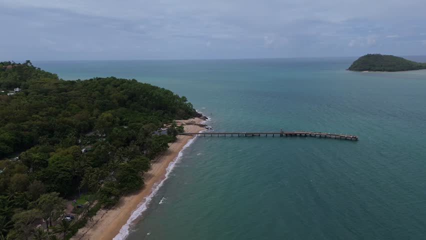 Drone flyover of Palm Cove beach and wooden jetty extending into the Coral Sea