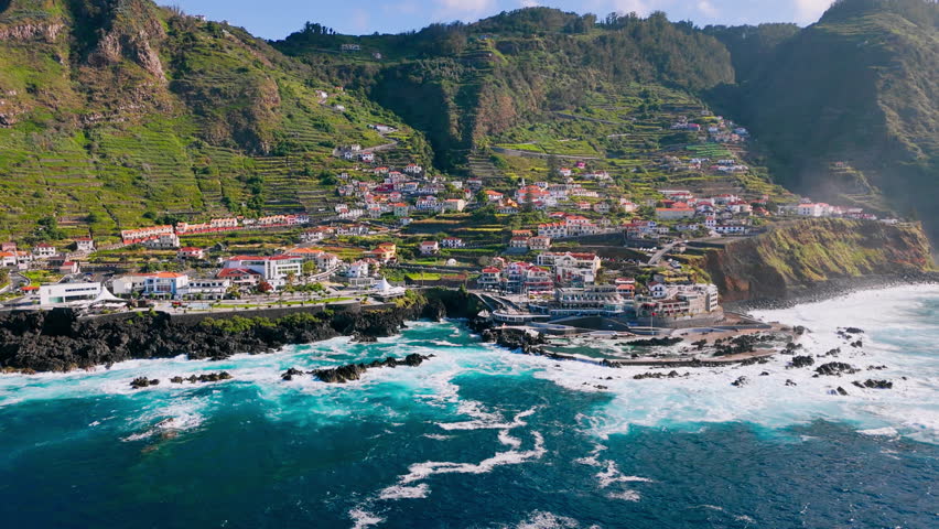 Aerial view of Porto Moniz coastline on Madeira Island with powerful Atlantic Ocean waves breaking against volcanic rocks in sunny weather