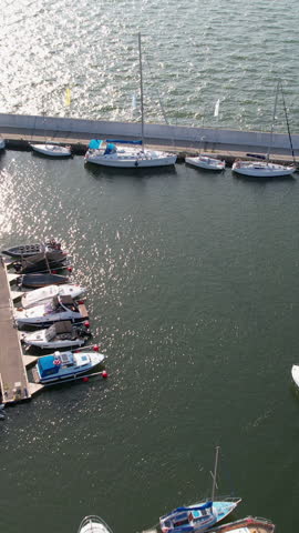 High angle aerial shot of various motorboats and sailing yachts docked at a modern marina pier in Gdynia, Poland. Perfect for travel, maritime, and luxury lifestyle content.