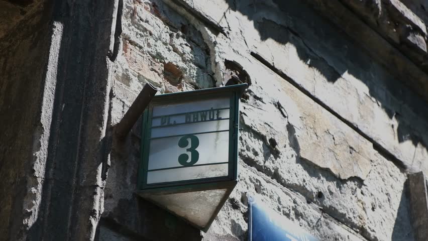 Close up of a vintage street number plate and old lantern mounted on a historic building facade.