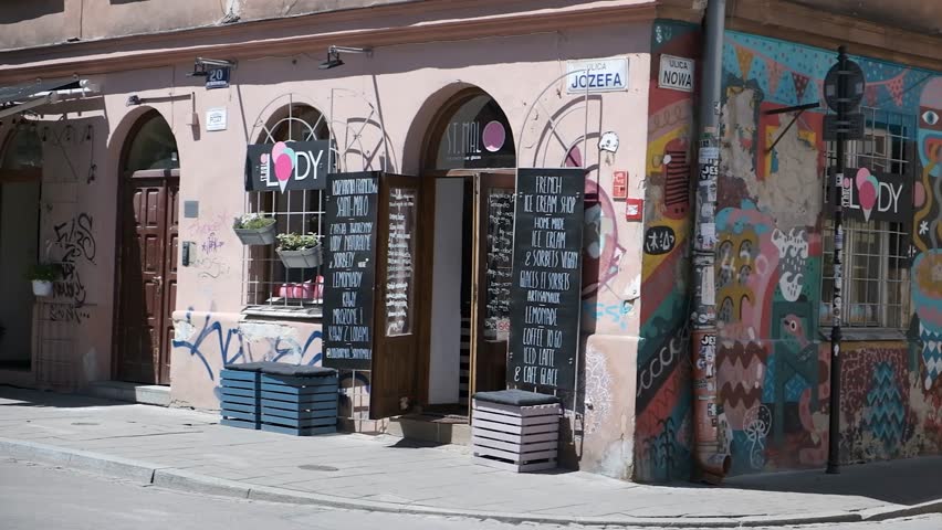 Colorful street corner with painted walls, cafe entrance and sidewalk shadows in Krakow Poland.