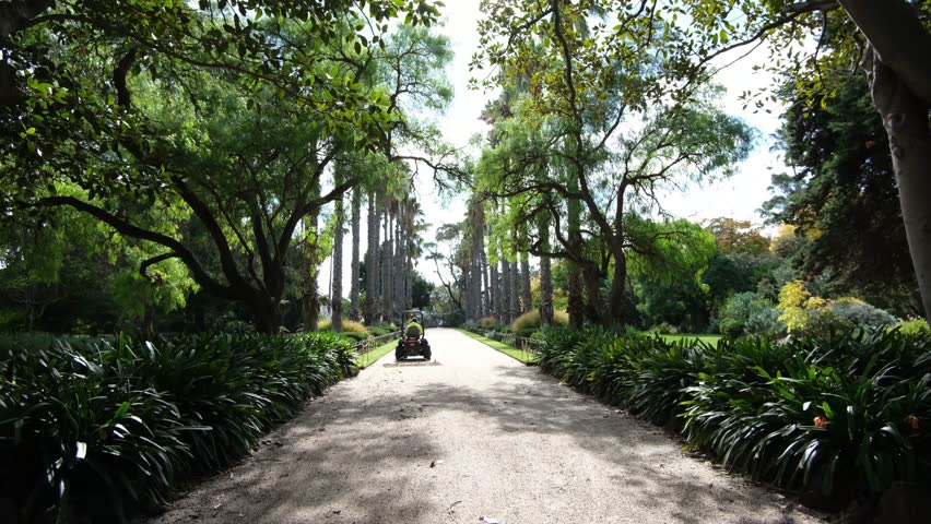 Williamstown Botanic Gardens in Melbourne, Australia, with a maintenance worker using a utility vehicle to level a gravel pathway in distance.