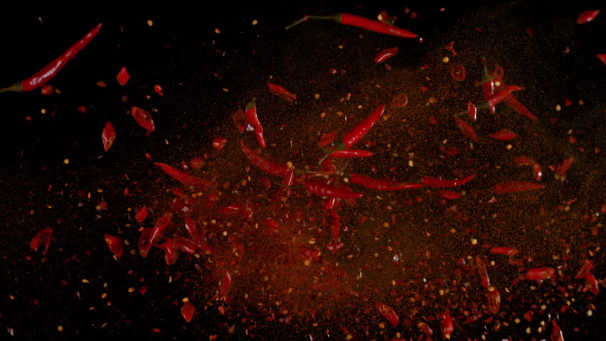 Chili Pepper Collision with Flying Powder and Seeds on Black Background