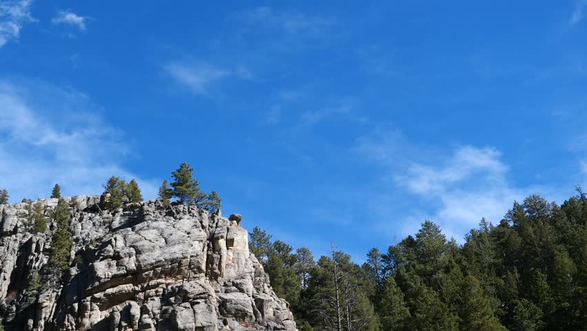 4K winter clouds drifting above rocky mountain cliffs and pine forest, Colorado