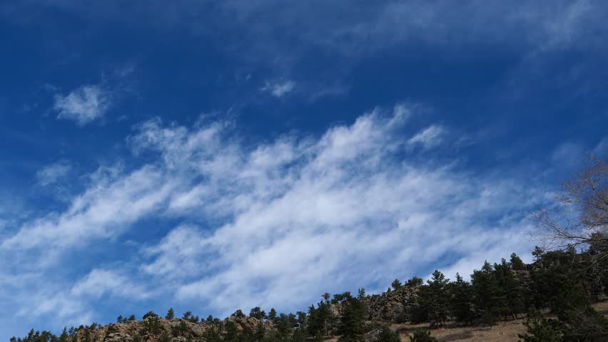 4K drifting winter clouds over mountain ridge and pine forest, Colorado