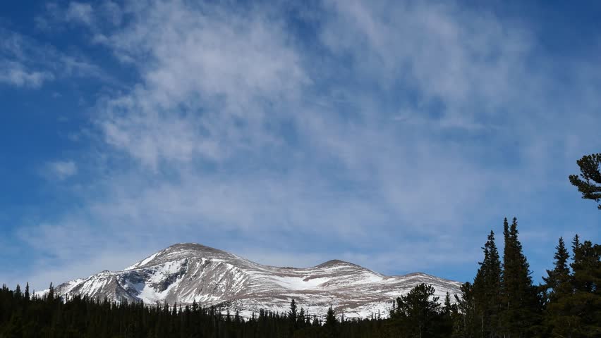4K winter clouds drifting above snow covered Rocky Mountain peak, Colorado