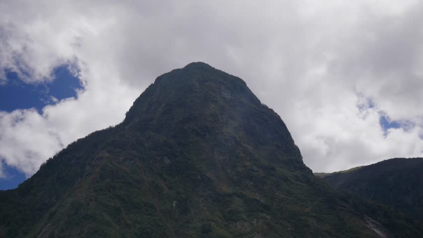 Close-up of a tall, rugged mountain rising above Doubtful Sound, highlighting jagged peaks, rocky cliffs, and dramatic alpine terrain in a remote wilderness.