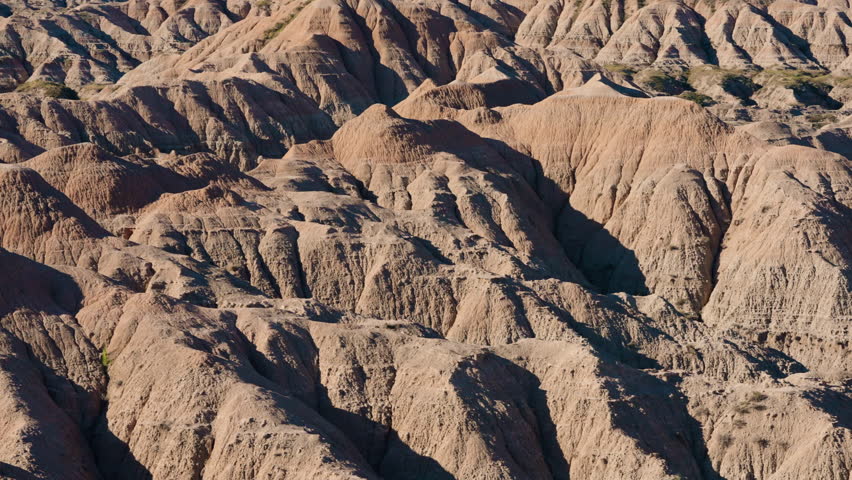 Bright layered stone ridges shaped by erosion across Badlands terrain, dramatic natural patterns, rugged desert geology, striking earth tones beneath open sky, iconic American wilderness scenery