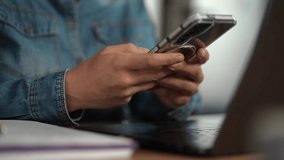 Close up of female freelancer hands typing on smartphone while working at desk with laptop in contemporary office space - Powered by Shutterstock - Get 15% off with code: PIKWIZARD15