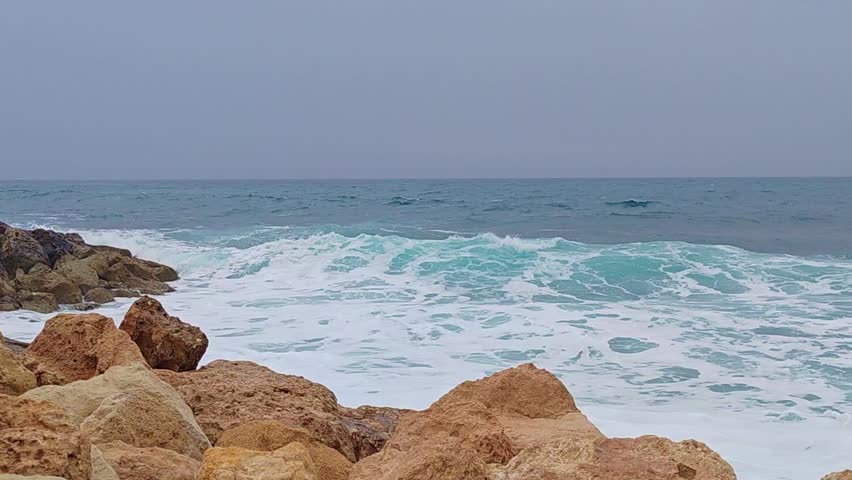 Scenic video of a rocky coast along the Paphos, Cyprus shoreline, waves crashing against the stone and turquoise waters of Mediterranean Sea 