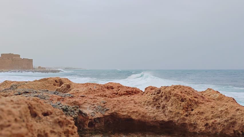 Scenic video of a rocky coast along the Paphos, Cyprus shoreline, waves crashing against the stone and turquoise waters of Mediterranean Sea 
