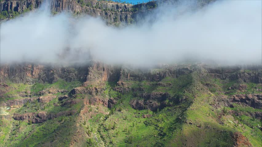Panoramic mountain landscape in Gran Canaria, Tasarte, along Ruta Ciclista near Inagua peak and Los Azulejos de Veneguera, with winding roads, green valleys and dramatic cliffs under blue sky.