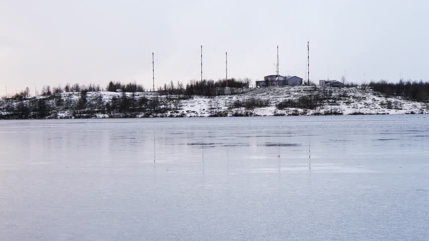 The lake, covered with the first ice, at sunset in early winter. The pale blue colors of the evening sky.