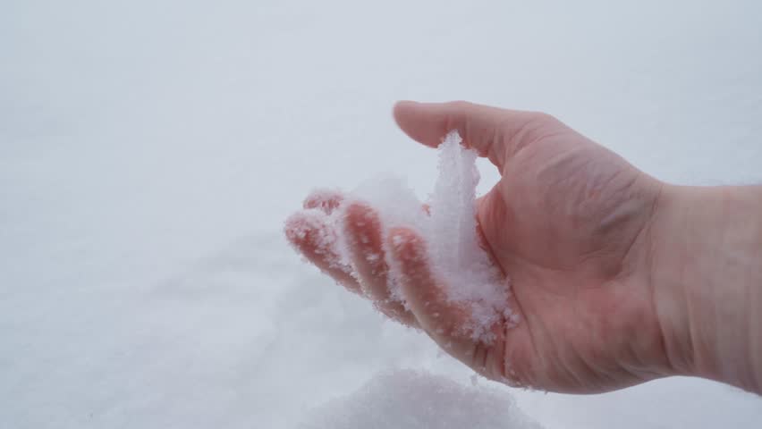 Hand kneading and touching snow close-up