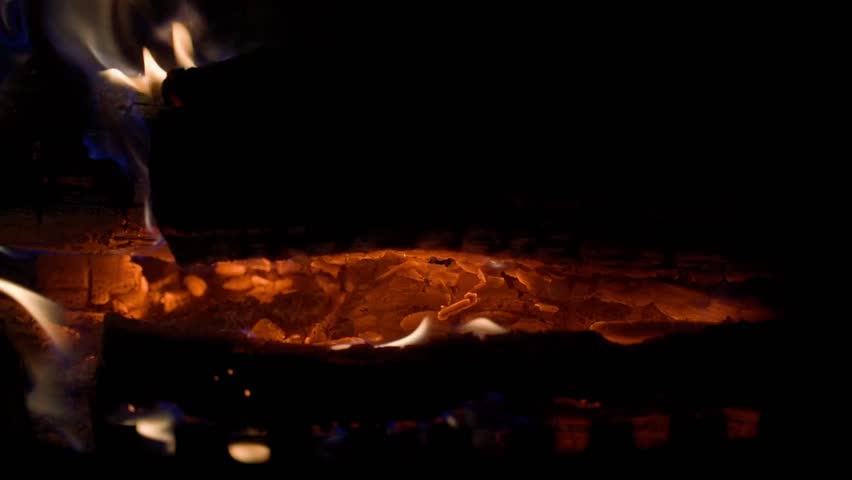 Slow motion as firewood burns in a fireplace in the dark, close-up