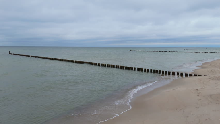 Exploring a beach with wooden pilings and calm waves at Lake Michigan shore