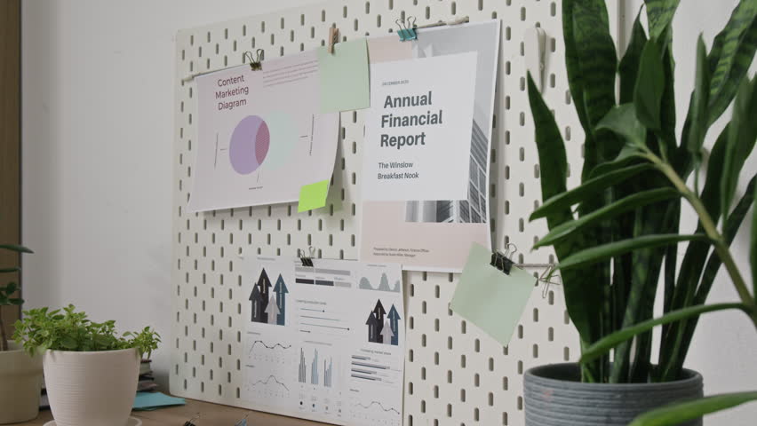 No people shot of paper printouts with graphs and financial statistics hanging on pin board in office workspace