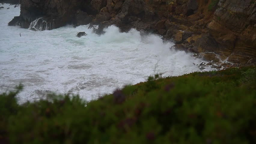 Stormy sea by a rocky coast in Sardinia in winter. Footage showing rough waves crashing against rocks, winter coastline, and turbulent water. 