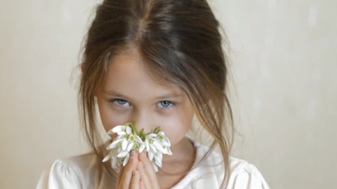 girl smelling flowers, admires a bouquet of snowdrops