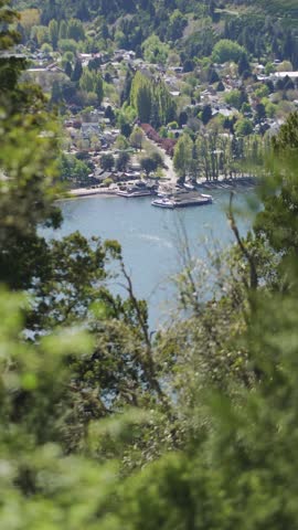 San Martín de los Andes on the shore of Lake Lacar surrounded by dense vegetation as hiker with a cap and backpack walks across the scene