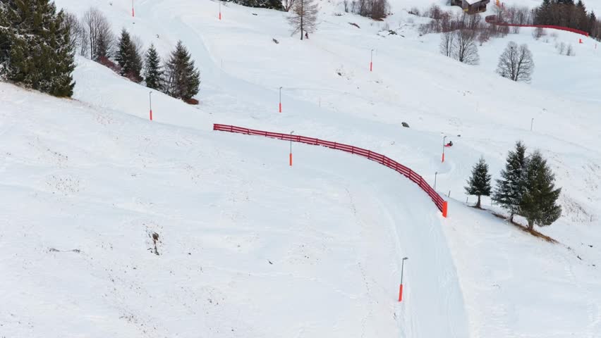 Elevated aerial perspective of snowmobile grooming ski slope with fresh powder on a mountain resort in the Alps during winter