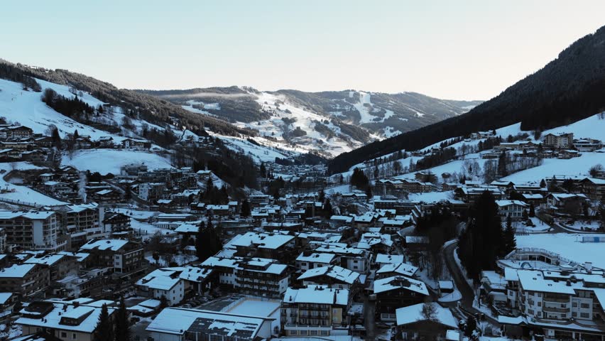 Elevated perspective over Saalbach, a winter resort town in the Austrian Alps, snowy rooftops during a cold sunny morning