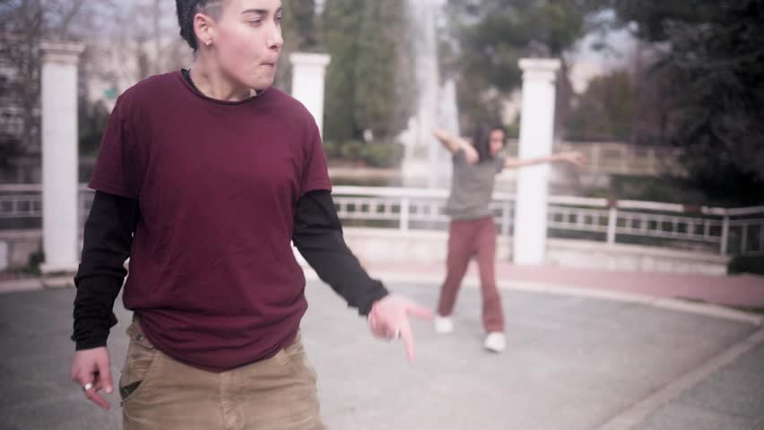 Woman beatboxing with a dancer freestyling in a park