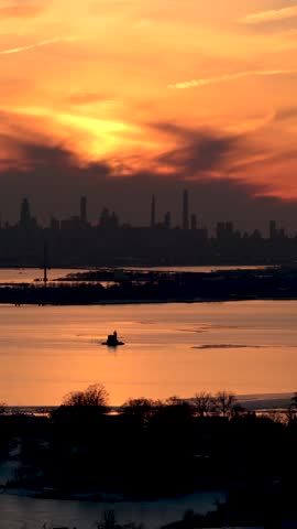 Picturesque golden sunset over the water with the iconic manhattan skyline silhouetted in the distance, viewed from port washington during a peaceful winter evening on long island