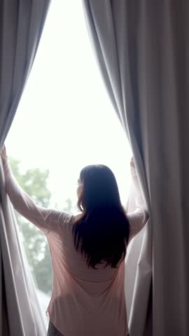 Beautiful Woman Opening Curtains to Welcome New Day. Young Lady Looking Out Window In Morning Light. Calm Adult Female Starting Daily Routine at Home. One Unrecognizable Person Wake up at Morning 4k