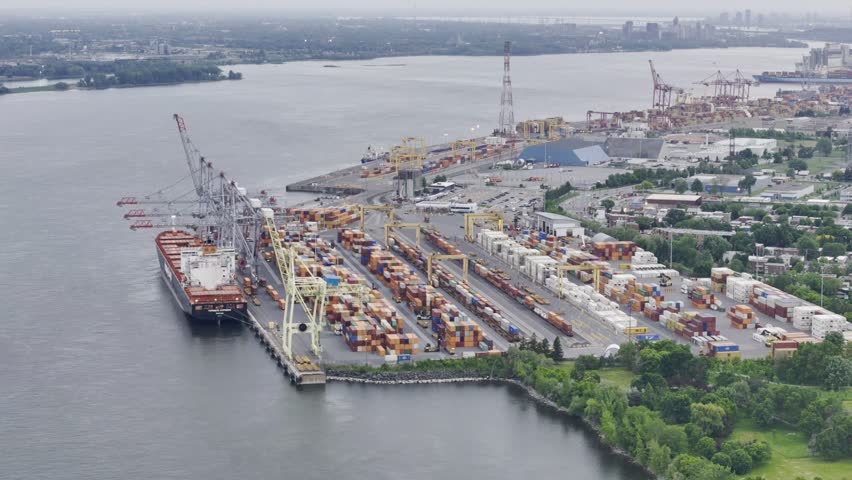 Aerial view of Montreal port with cargo containers, cranes and city skyline at sunset. g.