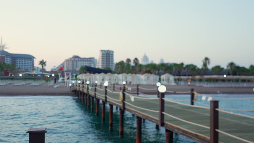 Mediterranean sea pier at sunset with glowing lamps and calm water