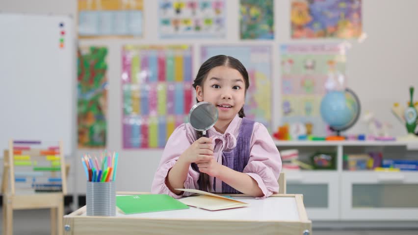 Young girl with braids inspects through magnifying glass at desk in bright classroom setting