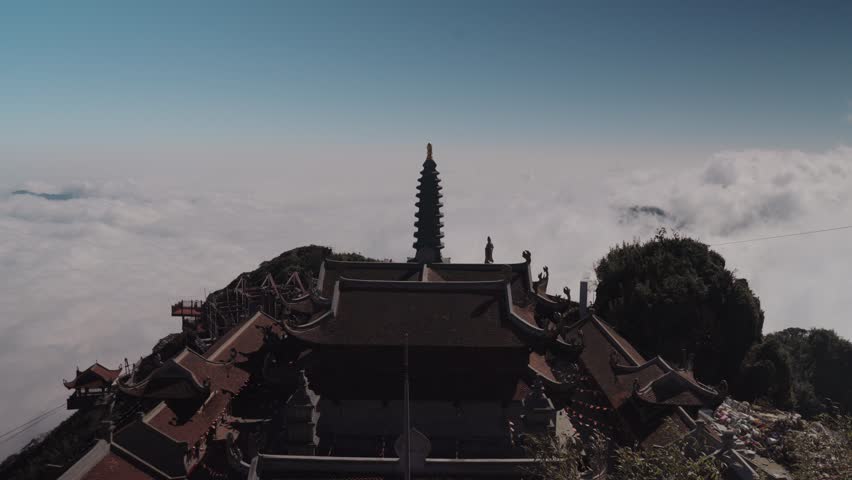 Temple architecture at the Fansipan summit in Sapa, Vietnam, featuring traditional roofs and stone structures set against clear blue sky and high-altitude mountain atmosphere.