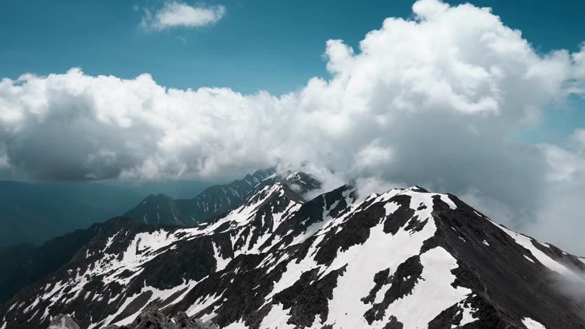TIME LAPSE VIDEO Snow-capped mountain peaks with dramatic clouds drifting across alpine ridge landscape
