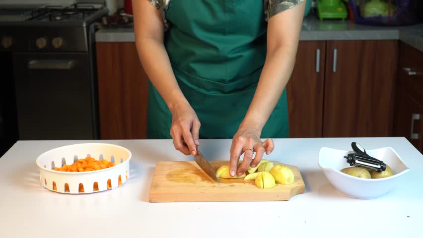 Woman Hands Cutting Potatoes on Wooden Board in the Kitchen